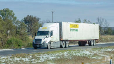 A white J.B. Hunt tractor pulling a J.B. Hunt intermodal container on a highway