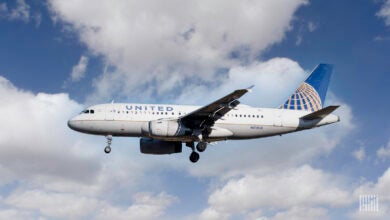 A United Airlines A310 on final approach to an airport against a blue sky with white clouds.