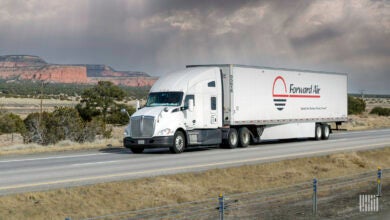 A white tractor pulling a white Forward Air trailer