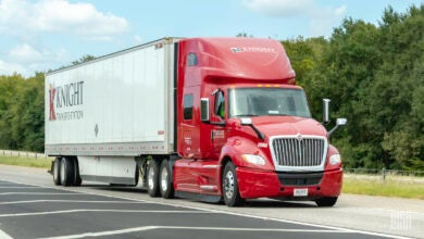 A red Knight Transportation tractor pulling a white Knight trailer on a highway