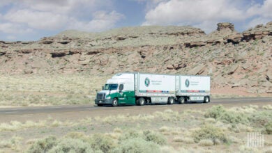 A green Old Dominion tractor pulling two LTL trailers in a desert