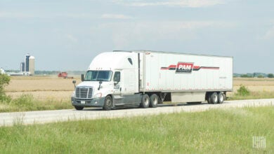 A white Pam tractor pulling a white Pam trailer on a highway