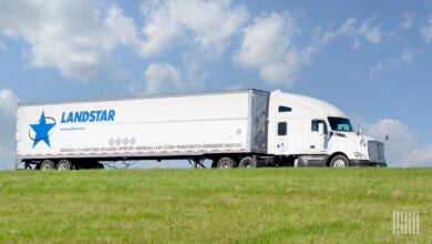 A white tractor pulling a Landstar trailer