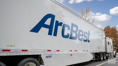 A white sleeper cab with an ArcBest trailer parked at a truck stop