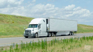 A white tractor pulling a white reefer trailer