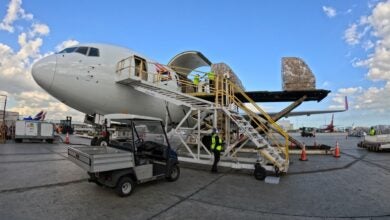 A cargo container on a large lift being loaded on a white cargo jet.