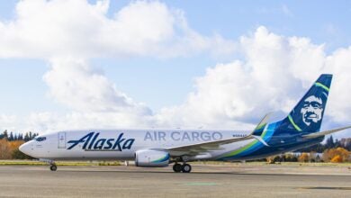 An Alaska Air Cargo jet with blue tail on runway. Side view.