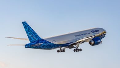 Blue/white Silk Way West Airlines cargo jet rises into the sky. View from the rear.