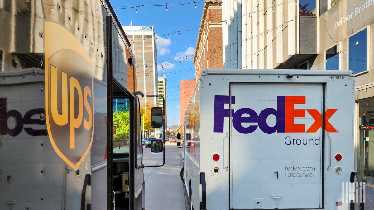 UPS and FedEx delivery trucks side by side on a city street