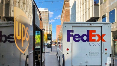 UPS and FedEx delivery trucks side by side on a city street