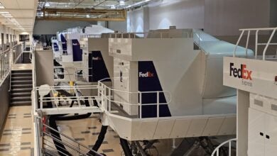 A bank of white and purple FedEx flight simulators in a building.