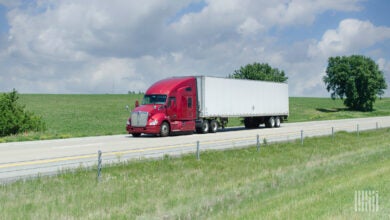 A red tractor with a white trailer on a highway