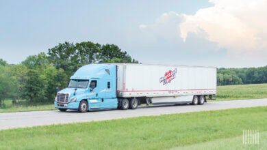 A powder blue Heartland tractor pulling a white Heartland dry van trailer