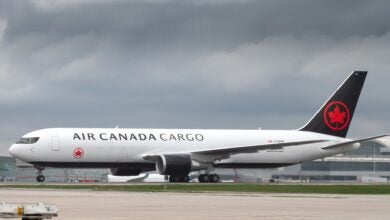 A black-tailed Air Canada Cargo jet moves on the runway on a cloudy day.