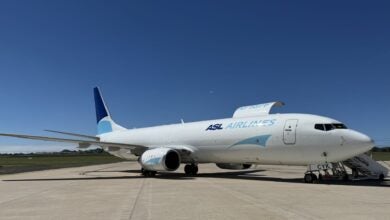 A 737-800 cargo jet with light-and-dark blue accents rests on the tarmac on a sunny day.