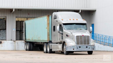 A tractor with an ocean container being unloaded at a warehouse