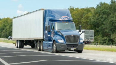 A blue NFI tractor pulling a dry van trailer on a highway