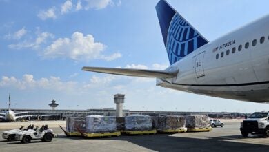 Rear view of United Airlines tail with with carts full of cargo ready to be loaded.