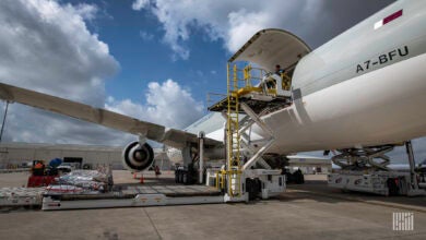 Close up of large jetliner with cargo door open, view from the tarmac behind the wing.