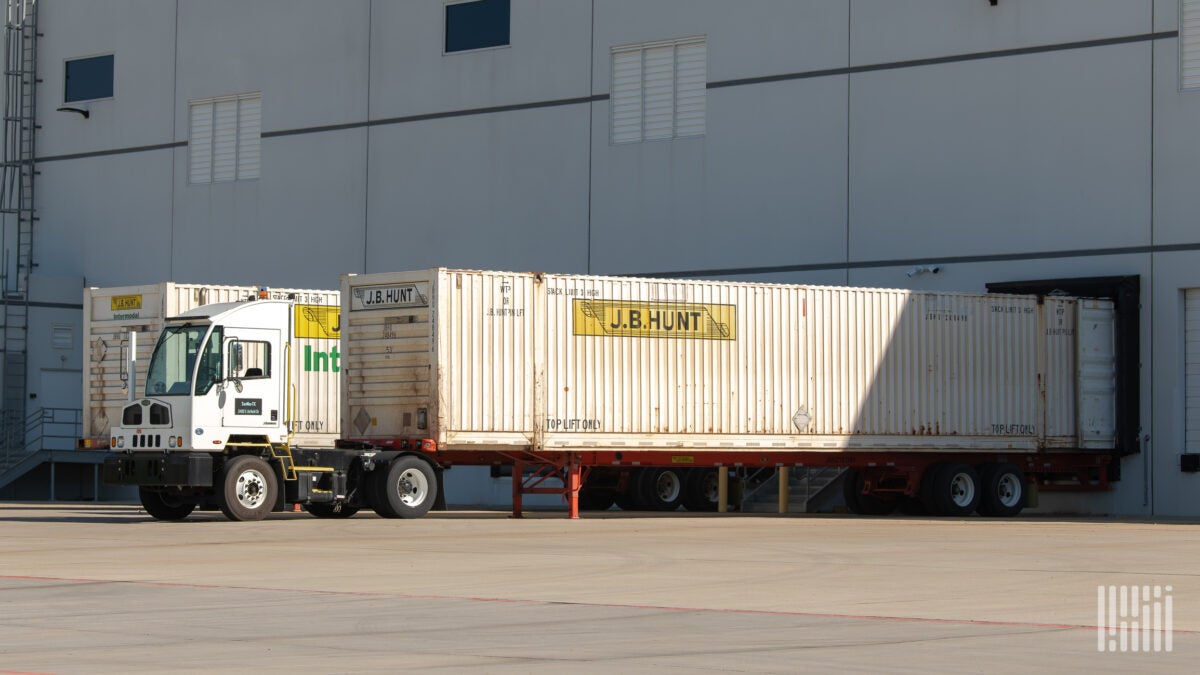 A yard truck with a JBI container backed up to a terminal door