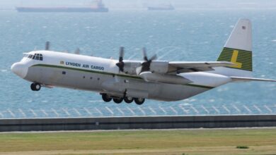 A Lynden Air Cargo propeller plane takes off with the ocean in the background.