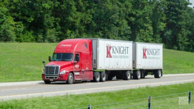 A Knight-Swift tractor pulling two pup trailers on a highway