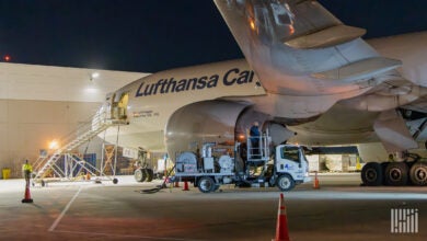 Side view of Lufthansa Cargo plane being loaded with pallets at night.