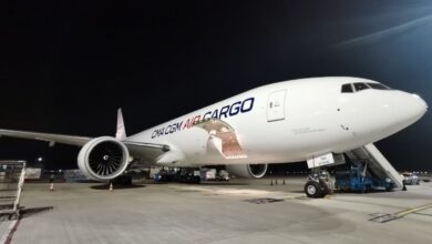 Night view of a CMA CGM Air Cargo freighter at airport with loading door open.