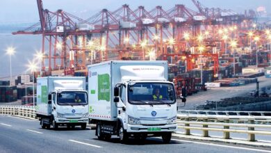 Images shows DB Schenker delivery trucks and container cranes.