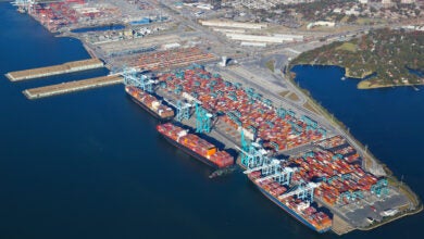 Image shows aerial view of container cranes, containers, piers and the ocean.