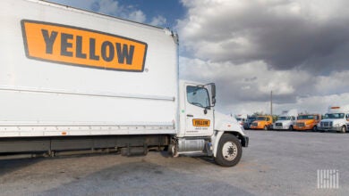 A Yellow straight truck parked at a terminal