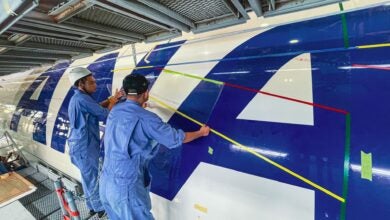 Aircraft mechanics in a hangar make improvements to the fuselage of a large jet.