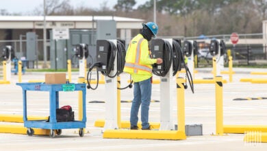 Man installing a truck charging port in parking lot.