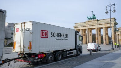 Image shows a Schenker truck and Berlin's Brandenburg Gate.