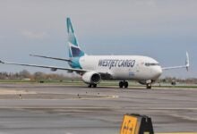 A teal-tailed WestJet Cargo plane rolls on the taxiiway on a gray day.