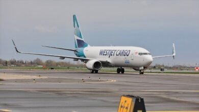 A teal-tailed WestJet Cargo plane rolls on the taxiiway on a gray day.