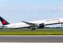 Air Canada jet with black tail and red maple leaf takes off from runway.