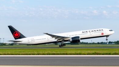 Air Canada jet with black tail and red maple leaf takes off from runway.