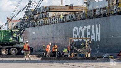 Images shows carg vessel and port workers.