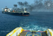 Image shows burning oil tanker towed by tugboat.