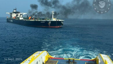 Image shows burning oil tanker towed by tugboat.