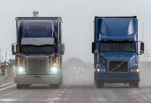 front view of two tractor-trailers on a rain-soaked highway