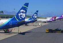 Close of up rear tails of Alaska Air jets on a sunny day at an airport.