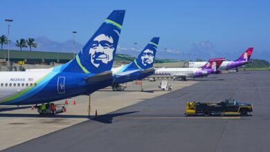 Close of up rear tails of Alaska Air jets on a sunny day at an airport.