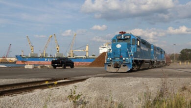 Image shows locomotives, ocean vessel, cranes.