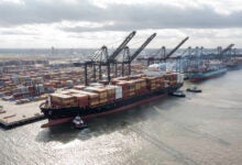 Image shows containers, dock, cranes and container ships