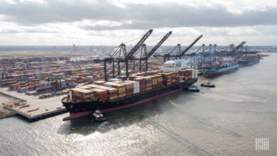 Image shows containers, dock, cranes and container ships