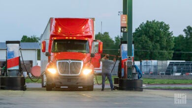 A truck driver cleaning windows while fueling