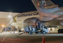 Night view of a tanker truck refueling a Lufthansa Cargo plane.