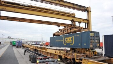 Image shows container cranes, double stack railroad cars, shipping container